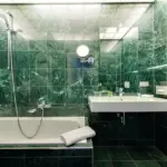 Badezimmer mit grünen Fliesen und Badewanne

