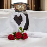 Bett mit Handtuch-Schwan und roten Blüten

