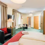 Hotelzimmer mit Sofa, Teppichboden und TV

