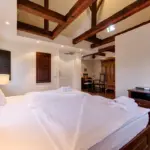 Schlafzimmer mit Holzbalken und Bettdecke

