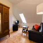 Raum mit Holzschrank, Sitzgruppe und Dachfenster

